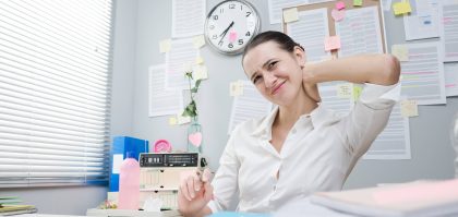 A woman holding her neck feeling neck pain while working in her office
